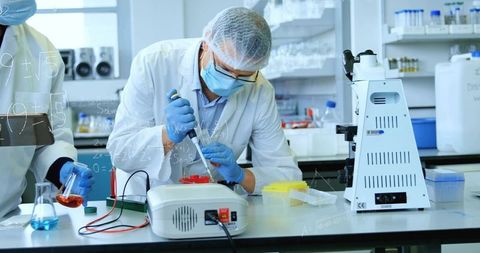 Scientist pipetting sample into microtube on lab bench with microscope and reagents