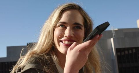 Young woman holding smartphone and smiling on rooftop, urban lifestyle and conversation