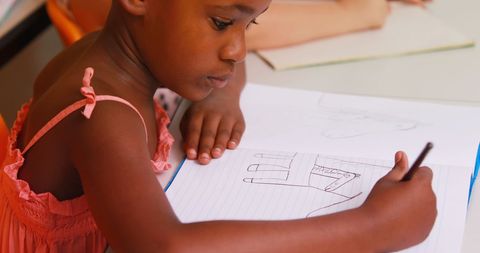 Schoolgirl Drawing in Classroom Notebook