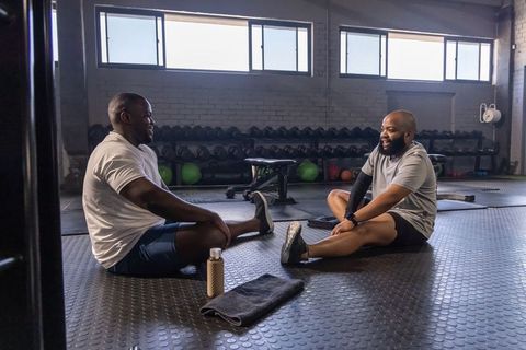 African american men stretching and chatting after strength training in industrial gym