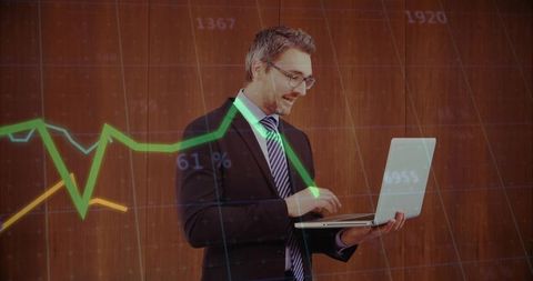 Businessman Analyzing Financial Graphics Using Laptop in Modern Office