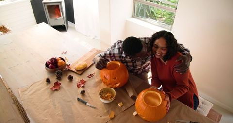 Happy Couple Carving Pumpkins for Halloween Festivity