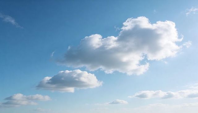 Sunlit cumulus clouds drifting across clear soft blue sky