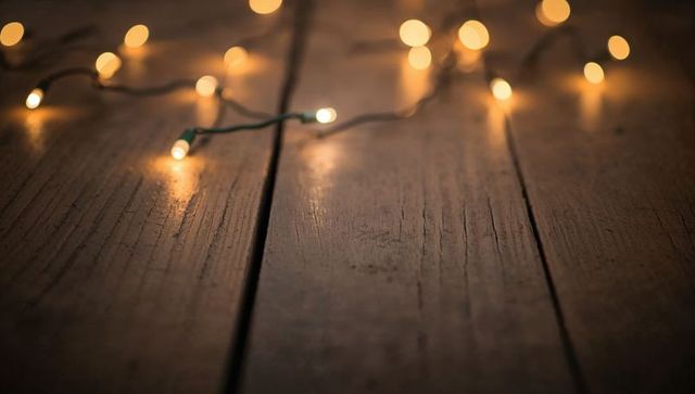 Fairy lights casting warm glow on rustic wooden planks with soft bokeh and grain