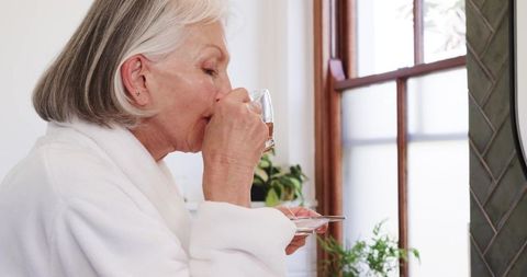 Senior Woman Enjoying Tea in Luxury Bathroom Setting