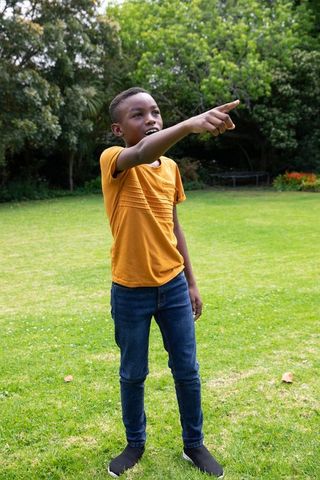 Joyful Boy Pointing in Sunny Garden