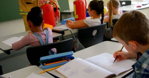 Firefighter teaching children fire safety in classroom