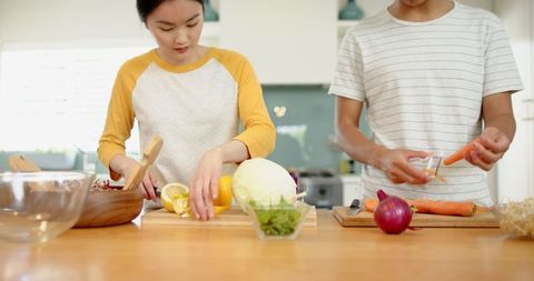 Friends cooking together in modern kitchen chopping vegetables