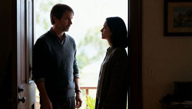 Couple standing at doorway having quiet conversation on threshold, backlit silhouettes conveying ten