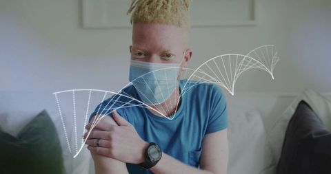 Young man wearing mask holding arm on sofa with dna overlay for vaccine and genetics concept