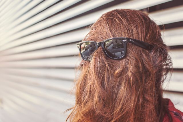 Creative image depicts person with long hair covering their face while wearing sunglasses. Perfect for humorous content, fashion blog posts, advertising related to eyewear, or editorial pieces on quirky or unusual trends.