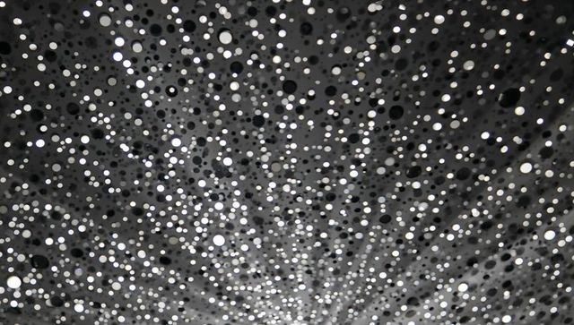 Monochrome bokeh explosion: radial macro dots creating depth and textured abstract pattern