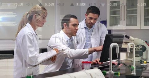 Research team collaborating at lab bench analyzing data on computer with microscope nearby