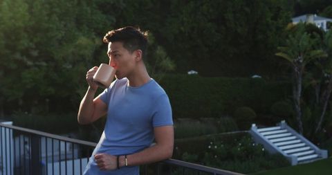 Man Relaxing with Coffee on Balcony at Sunset