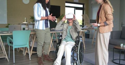 Diverse team guiding man in wheelchair using vr headset enabling inclusive collaboration