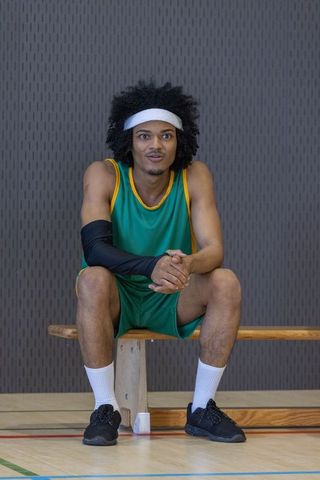 African American Basketball Player Resting on Court Bench