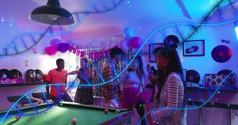 Friends celebrating birthday around pool table in neon lounge with balloons and vinyl