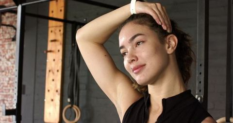 Woman exercising with neck stretch at modern gym