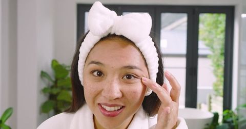 Asian Woman Practicing Skincare Ritual in Home Bathroom