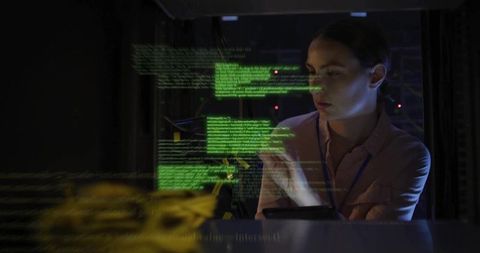 Female technician inspecting server rack with holographic green code in dark datacenter