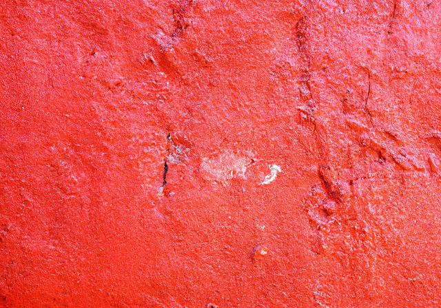 Vivid red textured wall close-up revealing unique surface details. Ideal for use in design projects, background layers, and adding a bold, vibrant touch to presentations or creative compositions.