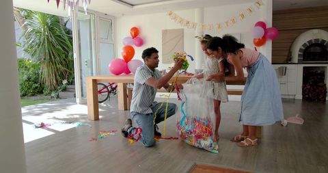 Family Cleaning Up After Birthday Party in Decorated Living Room