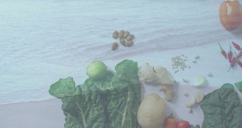 Rustic flatlay of dark leafy greens, potato and ginger on pale wood with ocean overlay