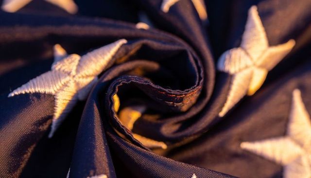 Macro swirl of navy blue flag fabric with embroidered white stars and visible stitching