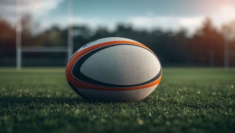 Rugby Ball on Green Field Beneath Clear Sky