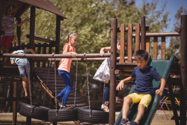 Children are enjoying various playground equipment outdoors. They are climbing, sliding, and having fun together. This image can be used for educational materials, advertisements for playground equipment, or articles about childhood activities and outdoor play.