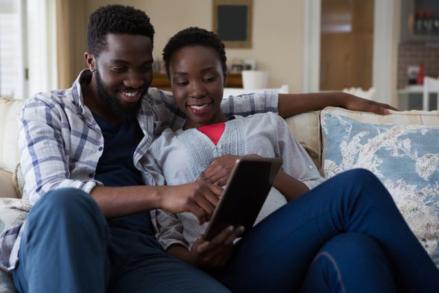 Couple using digital tablet in living room at home