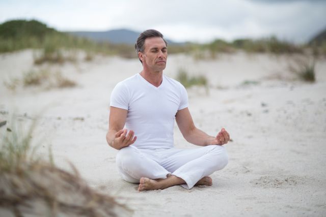 Mature man doing meditation on the beach