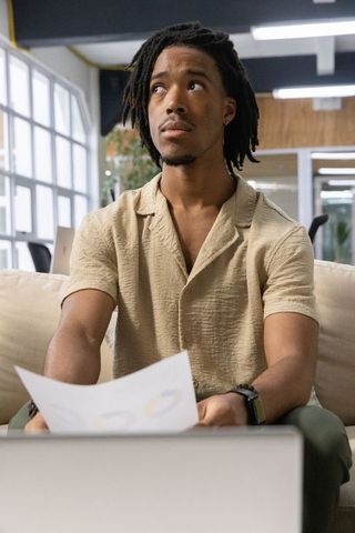 African american entrepreneur sitting couch analyzing charts with laptop in shared office