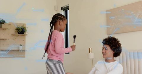 Smiling mother and daughter playing makeup in bright bedroom — family bonding and home fun