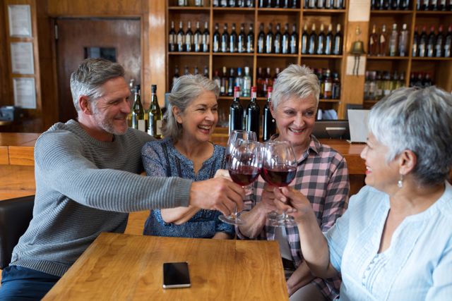 Group of smiling senior friends toasting glass of wine in restaurant