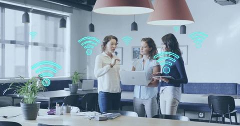 Women collaborating over laptop and tablet in modern open office with wi-fi graphics