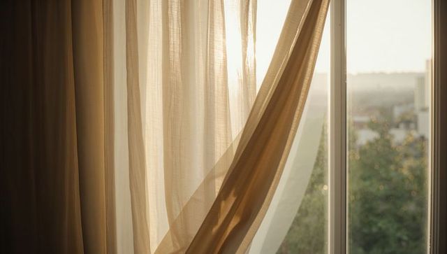 Sunlit Sheer Beige Curtains Billowing at Window with Soft Warm Morning Glow