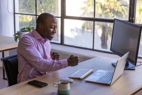 Joyful Businessman Celebrating Success at Modern Office Desk