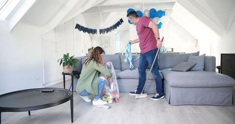 Couple cleaning up after party in stylish living room