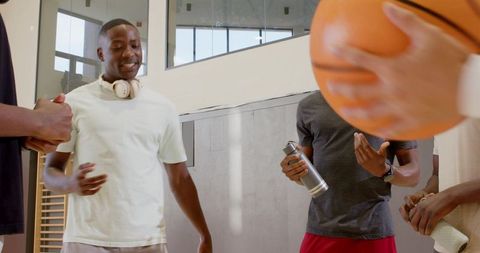 Friends chatting passing basketball at gym sideline showcasing camaraderie and teamwork