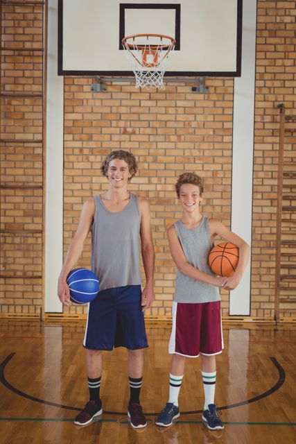 Portrait of smiling school boys holding basketball in the court
