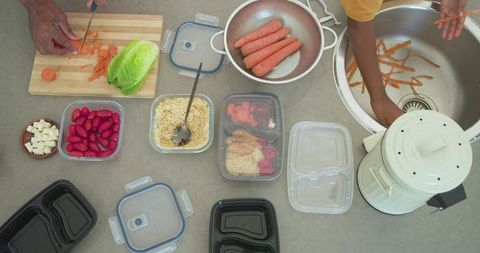 African american men preparing healthy meal prep with carrots, grains and containers on countertop