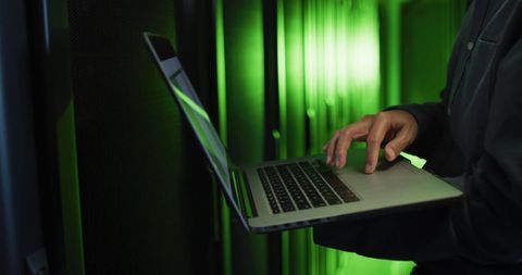 Engineer Analyzing Data on Laptop in Server Room with Green Light - Download Free Stock Images Pikwizard.com