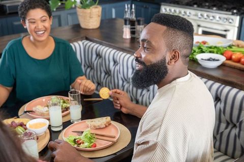 Happy couple dining on fresh salad and bread at home kitchen
