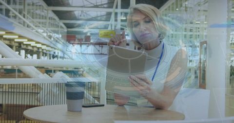 Businesswoman tapping tablet in modern warehouse with glass reflections and digital overlay