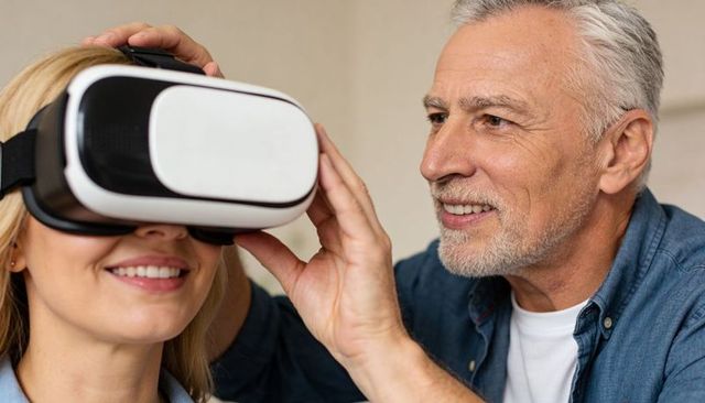 Mature man adjusting vr headset on smiling woman, couple trying virtual reality