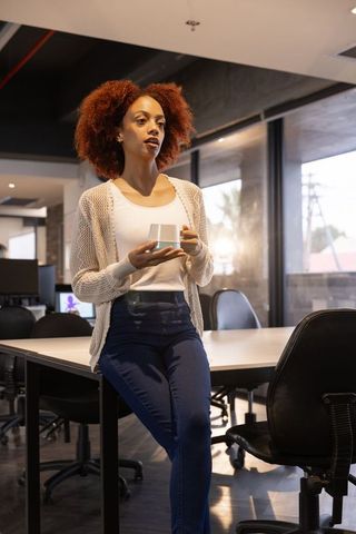 Confident professional woman enjoying coffee break in modern office