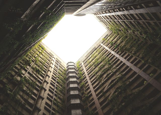 Tall building courtyard with green vines growing on walls, seen from an upward angle. Useful for illustrating urban architecture, city living, eco-friendly designs, or natural integration in modern settings.