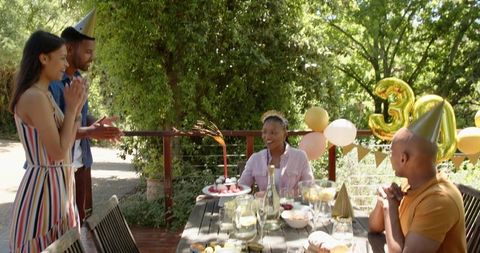 Cheerful Friends Celebrating Birthday Outdoors with Lively Decorations