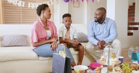 African American family celebrating son's birthday at home, sharing cupcakes and smiles